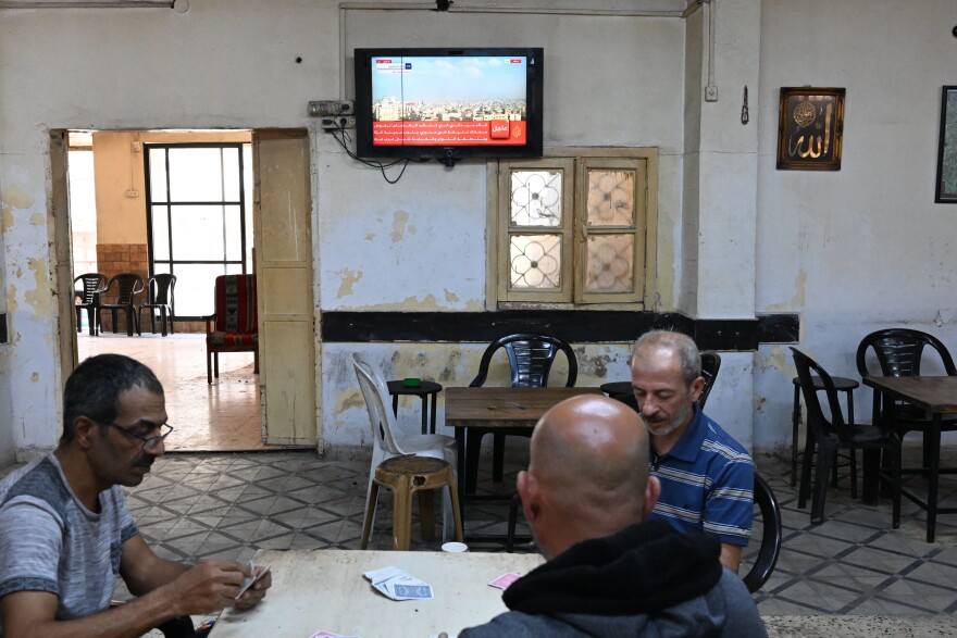 Men play cards in a coffee shop and watch news from Gaza in Ramallah in the West Bank.