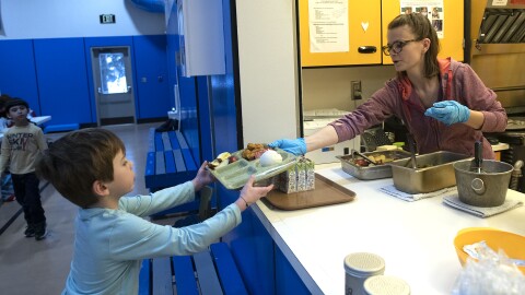 Dani Koschak passes a hot lunch to a student at Moose Pass School. The small school serves students grades kindergarten through 8.