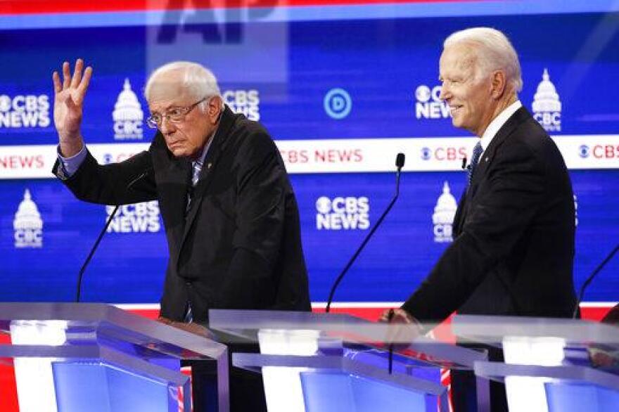Bernie Sanders points and grimaces, left, and Joe Biden smiles, right, at their respective debate stage lecterns.