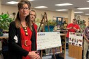 Cynthia Saunders speaks near a large check written to support literacy