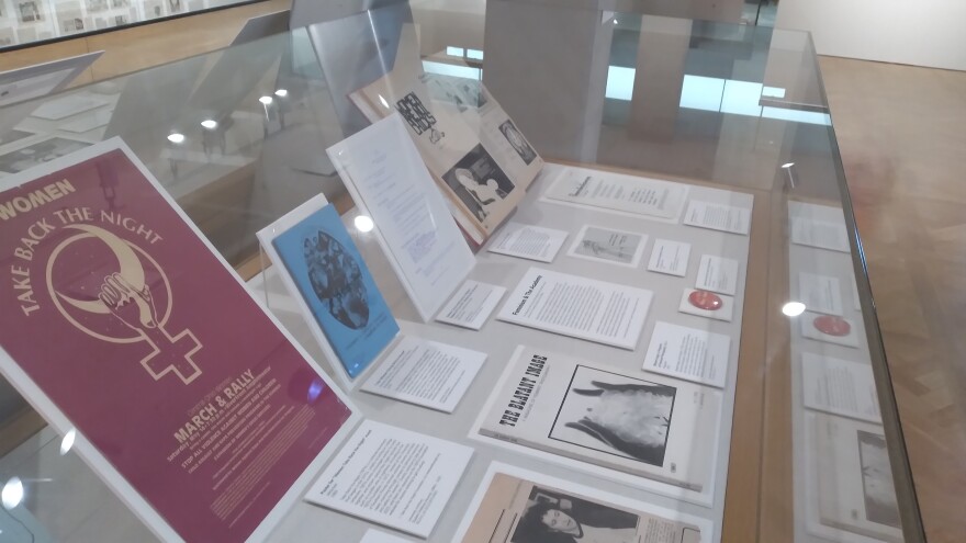 Display case with posters, placards and other materials in "Abject Object: Feminism, Art & the Academy"