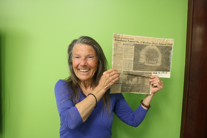 Karall Heimann holds up a newspaper with an article about her and smiles.