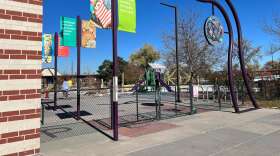 A mostly empty playground behind a brick building.