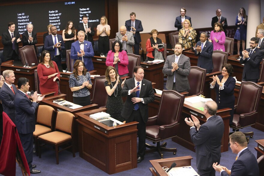 Senate president Bill Galvano, R-Bradenton, center, acknowledges his fellow senators applause at his retirement ceremony during session Thursday, March 12, 2020 in Tallahassee, Fla. Republican Sen. Wilton Simpson will take over for Galvano as leader of the chamber for the Florida Legislature's 2021 session. (AP Photo/Steve Cannon)