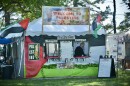 A white tent is decorated in Palestinian decorations. A woman is working inside the booth.