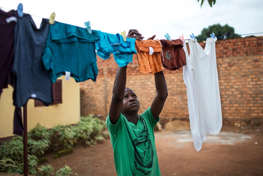 Ghislain-Oxwold Ngoaporo, a 17-year-old member of the Flambeaux scouts, hangs up laundry at his home in Bangui. Members of the scouts learn to be responsible for household tasks like laundry, cooking and cleaning — roles typically delegated to women in the Central African Republic.