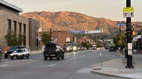 Cars drive on a street, with a mountain in the distance.