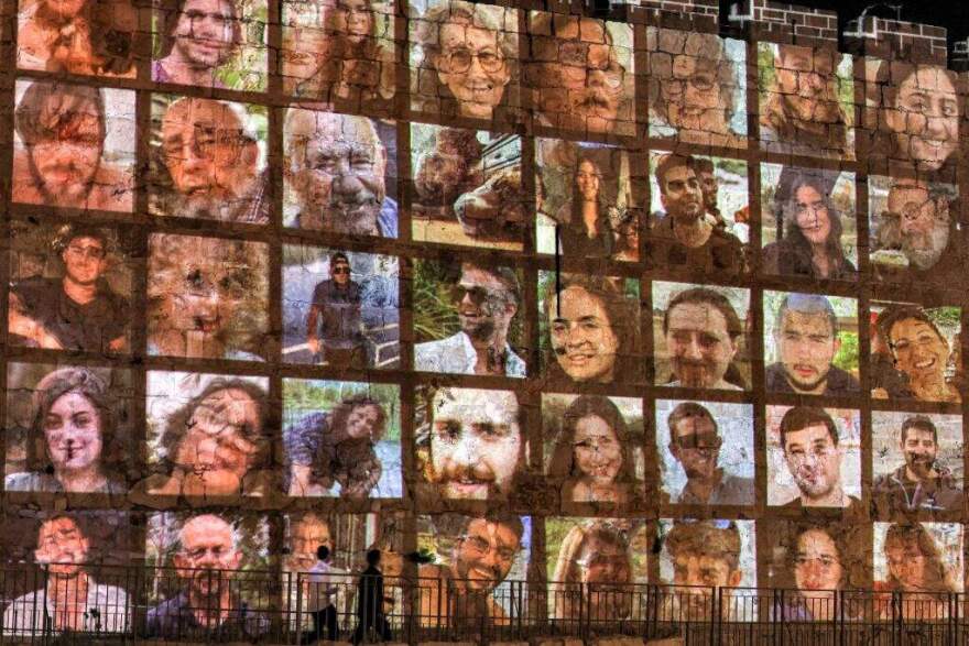 People walk outside the walls of the old city of Jerusalem, on which are projected pictures of the hostages abducted by Palestinian militants on the October 7 attack and currently held in the Gaza Strip, on November 6, 2023, amid the ongoing battles between Israel and the militant group Hamas. (Photo by AHMAD GHARABLI / AFP) (Photo by AHMAD GHARABLI/AFP via Getty Images)