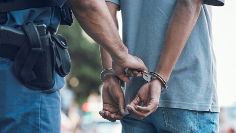 a police office handcuffs a man, the man has his hands cuffed behind his back
