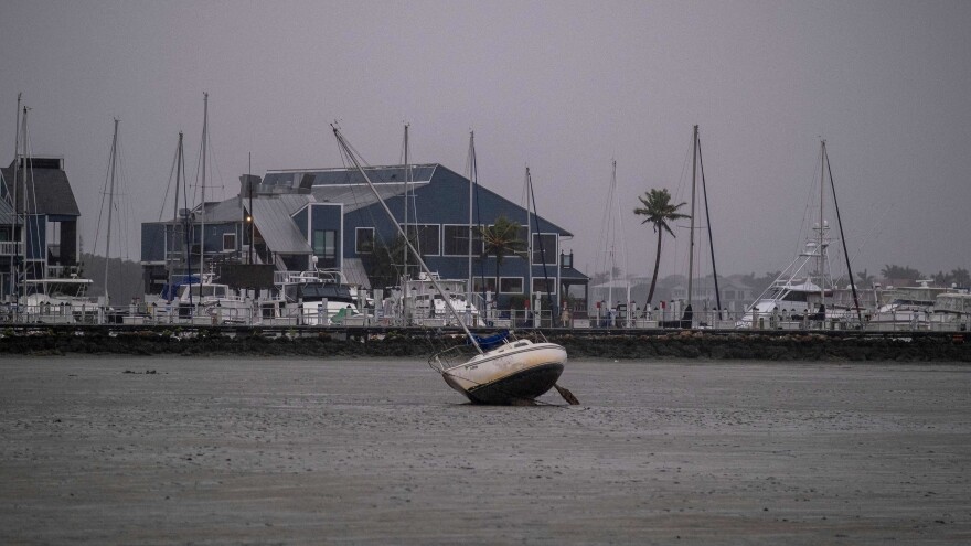 A sailboat lies on mud at the bottom of Charlotte Harbor as water receded ahead of Hurricane Ian in Punta Gorda, Fla.