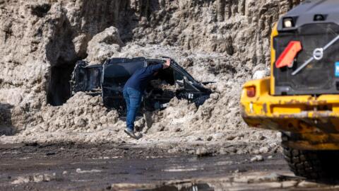 A Somerville city official looks inside the van after they unearthed it from a massive pile of snow in a vacant lot on Washington Street. (Jesse Costa/WBUR)