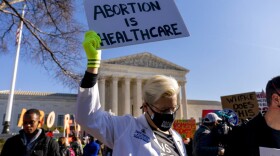 FILE - A woman holds a poster that reads "Abortion is Healthcare" as abortion rights advocates and anti-abortion protesters demonstrate in front of the U.S. Supreme Court, Dec. 1, 2021, in Washington, as the court hears arguments in a case from Mississippi, where a 2018 law would ban abortions after 15 weeks of pregnancy, well before viability. As the Supreme Court court weighs the future of the landmark 1973 Roe v. Wade decision, a resurgent anti-abortion movement is looking to press its advantage in state-by-state battles while abortion-rights supporters prepare to play defense. (AP Photo/Andrew Harnik, File)