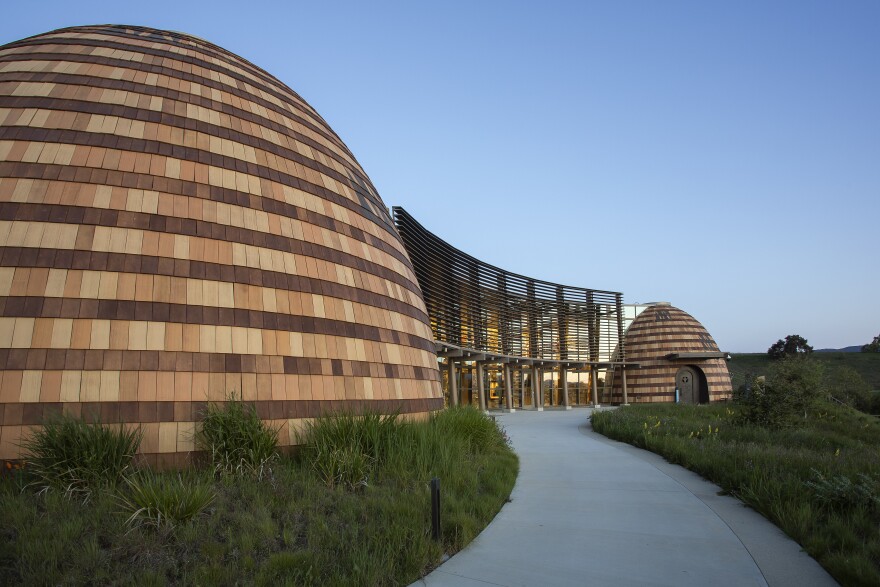 Two wood-paneled, domed buildings with an entryway in the middle.