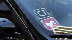 A driver displaying Lyft and Uber stickers on his car (Richard Vogel/AP)