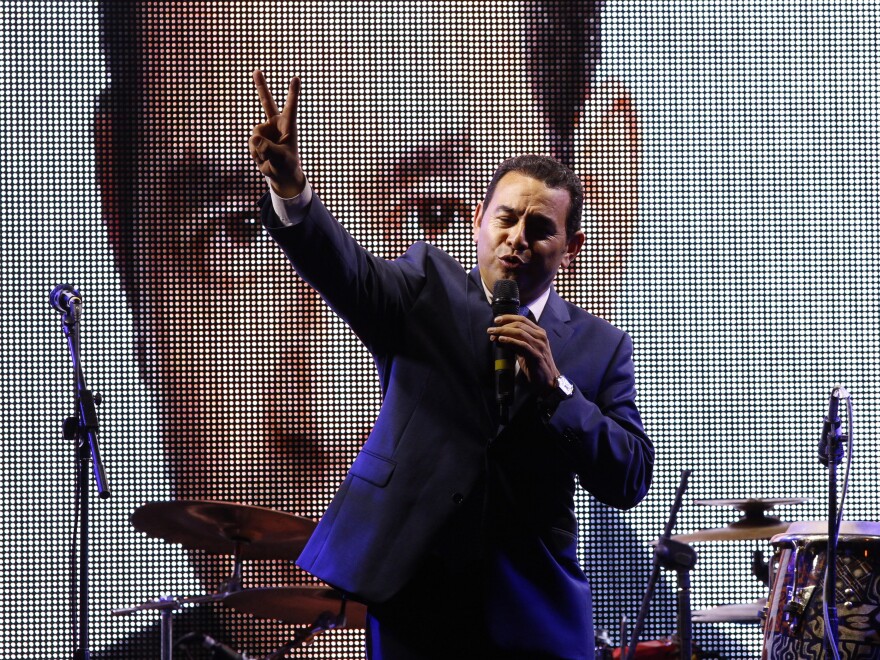 Television comedian and presidential candidate for the National Front of Convergence party Jimmy Morales, flashes a victory sign to his supporters at his party headquarters in Guatemala City, Sunday night. (AP Photo/Luis Soto)