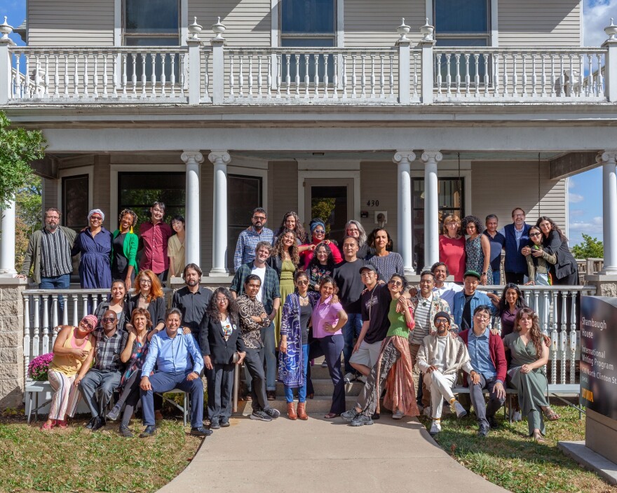 A group of people posed in front of a large house.