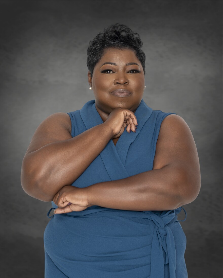 A woman poses against a gray studio backdrop.