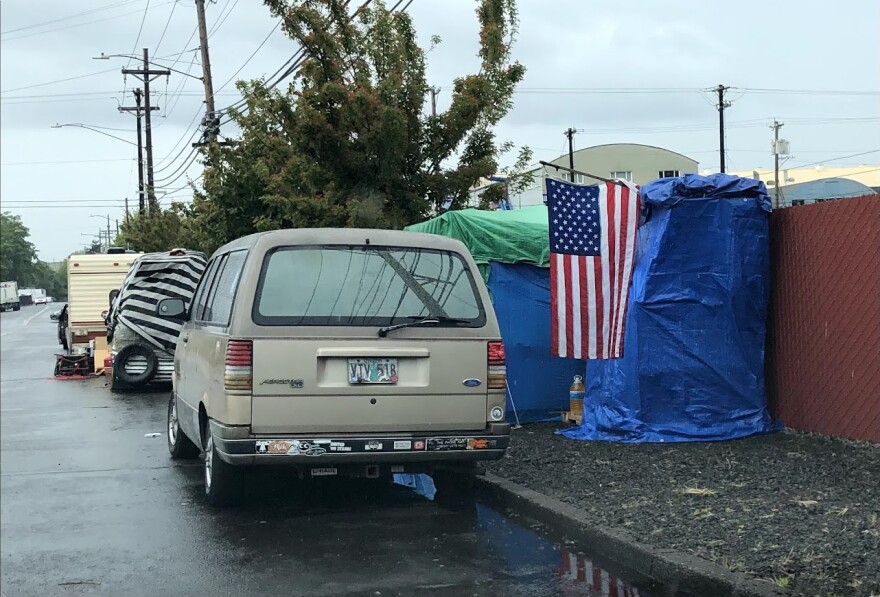 A row of vehicles and tents form a homeless encampment in Oregon.