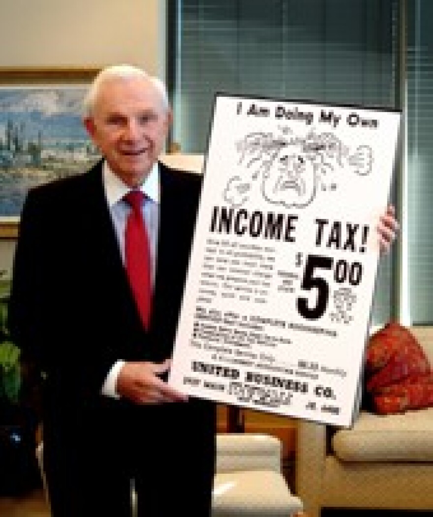Henry Bloch holding a picture of the newspaper ad that launched the tax preparation industry.