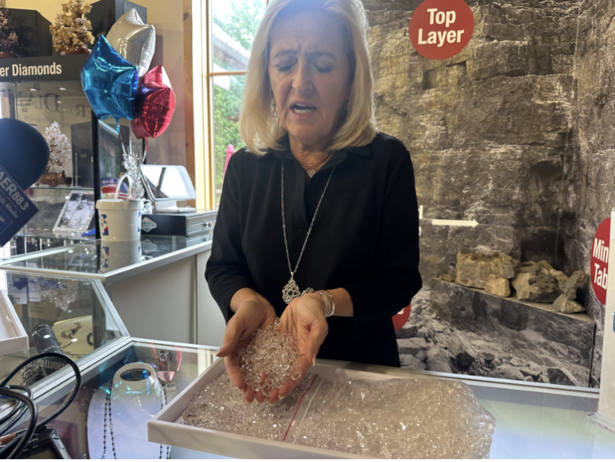 The owner of the Herkimer Diamond Mine looks over a tray of quartz crystals while scooping several hundred in her hands.
