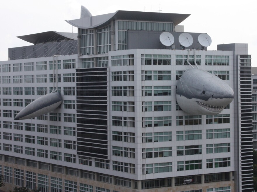 Chompie, a giant inflatable shark that measures 446 feet long, peeks out of the global headquarters building of Discovery Communications.