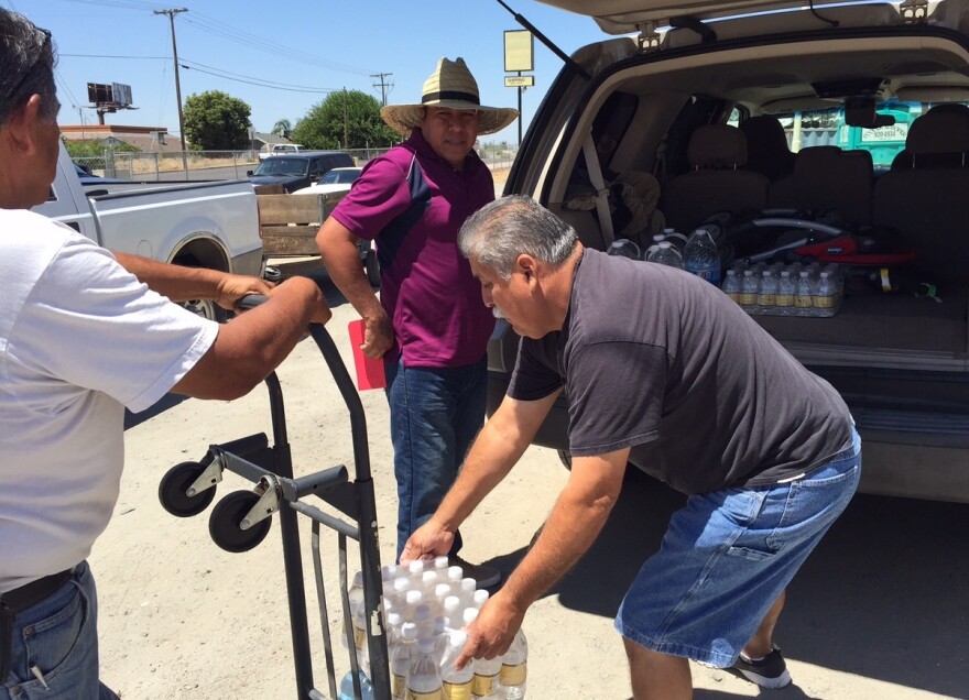 Pastor Frank Olmedo of the Spanish Church of the Nazarene in Porterville Calif., loads cases of bottled water into Humberto Hernandez's Suburban. These aid stations are a lifeline here, where residents like Hernandez have been living without water for more than six months.