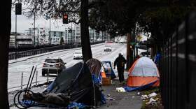 A pedestrian walks past an encampment of tents after crossing Hoyt Street in Portland, Oregon on Jan. 24, 2024. (Patrick T. Fallon/AFP via Getty Images)