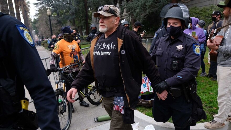 A demonstrator is detained and released after questioning at a pro-Trump rally in downtown Sacramento on Jan. 6, 2021.