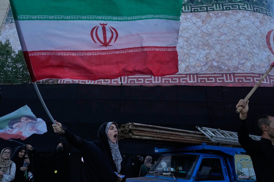 A woman waves an Iranian flags as she chants slogans against Iran and U.S. talks at the Islamic Revolution square in Tehran, Iran, Sunday, June 14, 2026. (AP Photo/Vahid Salemi)