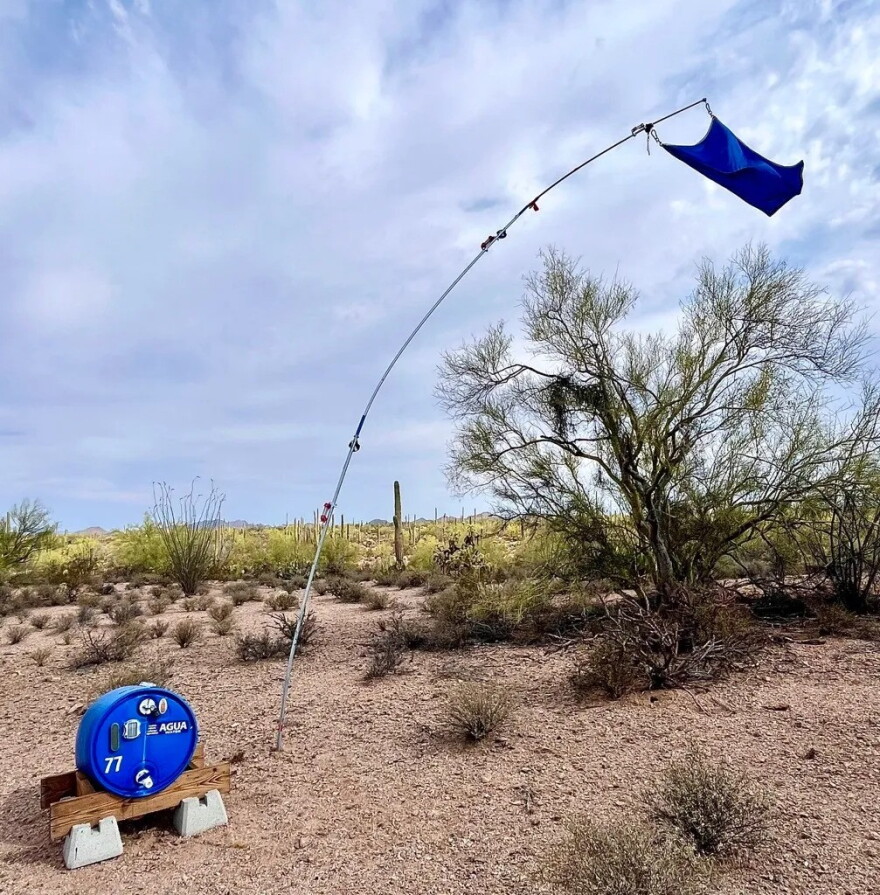 A makeshift flag flies above a water barrel in the desert.