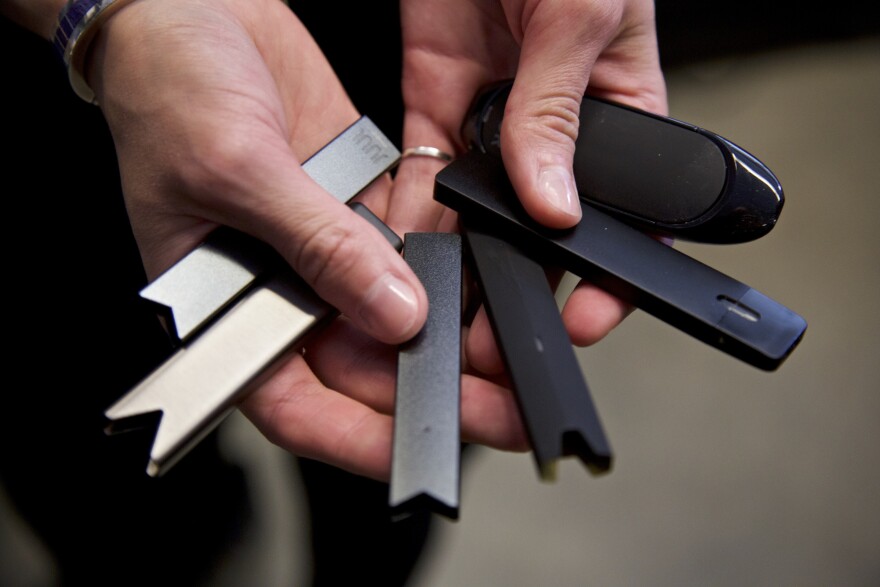 FILE - In this April 16, 2019 file photo, a researcher holds vape pens in a laboratory in Portland, Ore. According to a Centers for Disease Control and Prevention report released on Wednesday, Sept. 9, 2020, vaping rates among U.S. teenagers fell dramatically in 2020. The drop comes in the wake of 2019’s outbreak of vaping-related illnesses and deaths. (AP Photo/Craig Mitchelldyer, File)