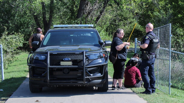 Local community advocate AlmaAnn Klaassen-Jones (center) talks to a police officer at the entrance of Chapin Park on Monday morning. Multiple volunteers and groups were allowed to help finish moving people out of the park.
