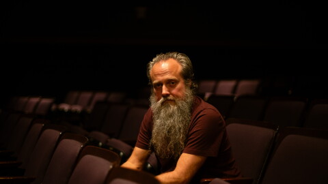 a man posing for a photograph in an empty theater 