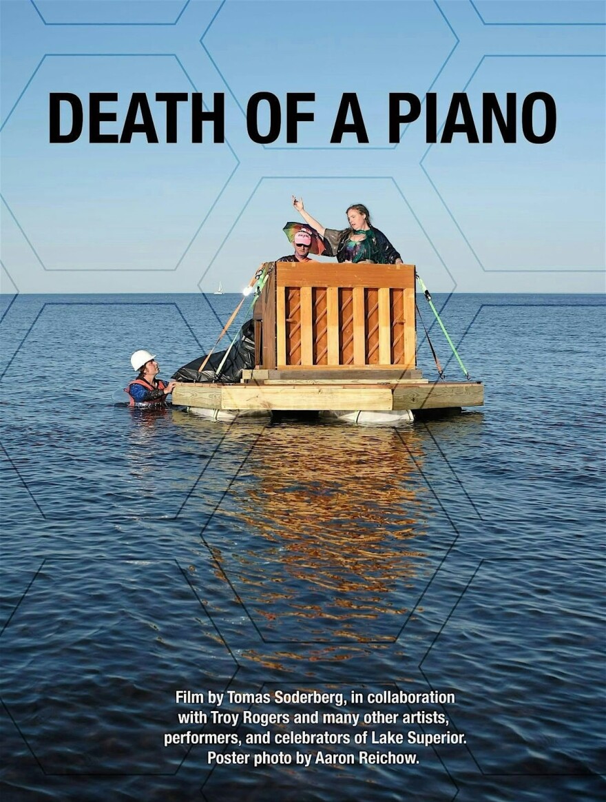 Poster for "Death of a Piano" a film by Tomas Soderberg; photo of two people on a makeshift raft performing with a piano, one person in the water with a hard hat