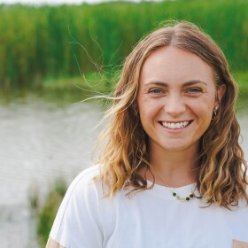 KU Graduate Researcher Bre Waterman stands at the edge of some wetlands.