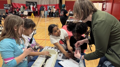 Person shows young kids how to measure a fish.