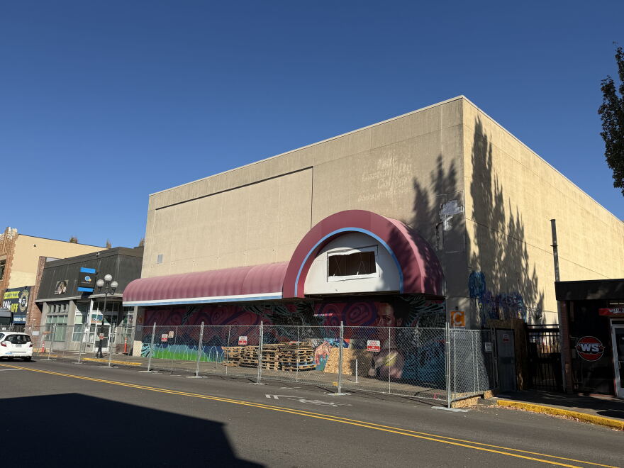 A building on a city street surrounded by a metal fence. 