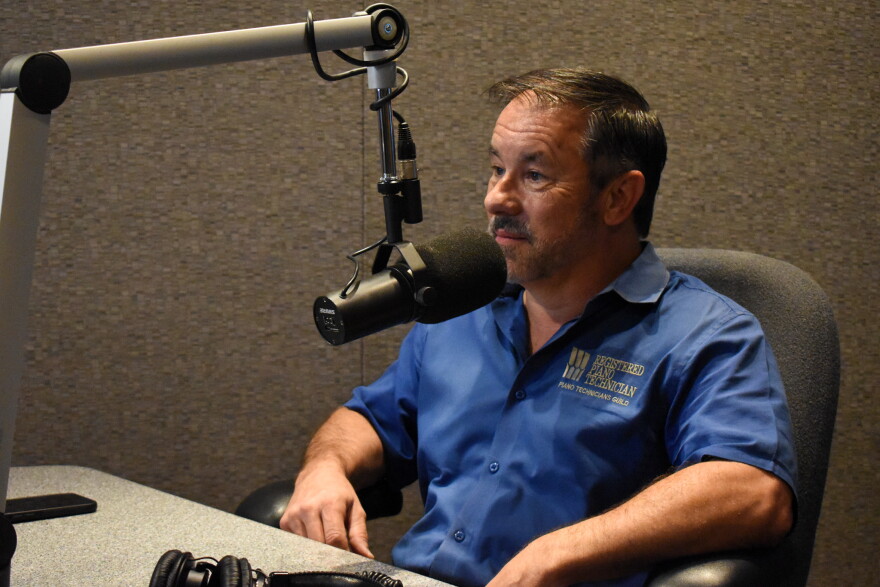 Scott Helms wearing a blue collared shirt sitting at a desk behind a microphone