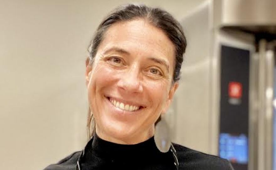 Woman in apron smiling into camera.