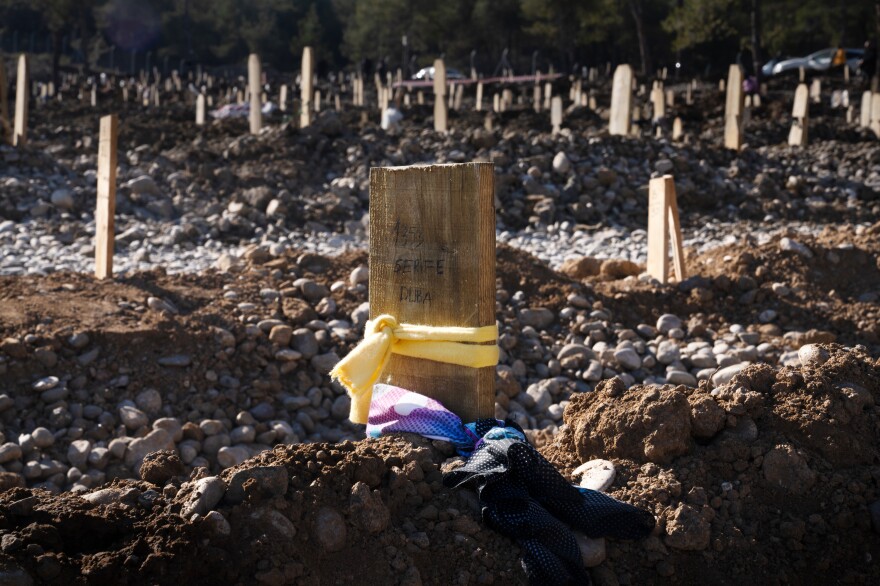 Scarves are tied to a wooden plank grave marker.