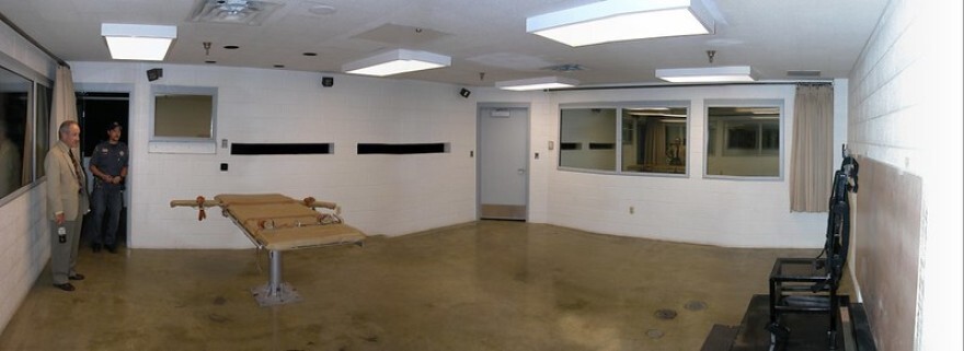 A photo of the execution chamber at Utah State Prison in Draper, Utah. The platform on the left is used for lethal injection. The seat on the right and the two narrow gun ports on the far wall of the room are used for execution by firing squad.