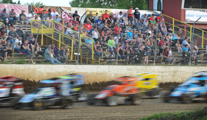 Competitors in the POWRi midget racers fly around the track in the last laps of their feature race Saturday at Valley Speedway in Grain Valley, Missouri. Fans crowded the grandstands as well as overflowed to the perimeter areas where dirt and grit from the track often pelted spectators.
