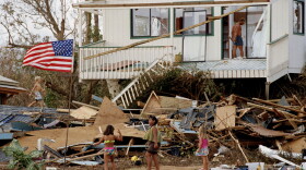 FILE - Children play in the rubble left by the fury of Hurricane Iniki, Sept. 15, 1992, at Brennecke's Beach near Poipu Beach, Hawaii, on the island of Kauaʻi. 