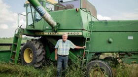 Dennis Kellogg proudly stands next to his John Deere combine from the 1970s. He said he'll use this equipment to harvest his crop later this year. 