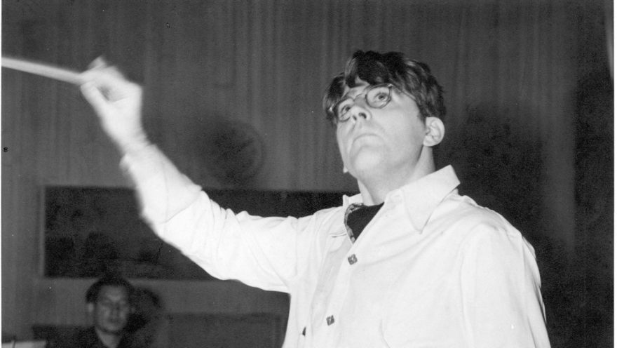 A black and white image of Meredith Willson conducting an orchestra.