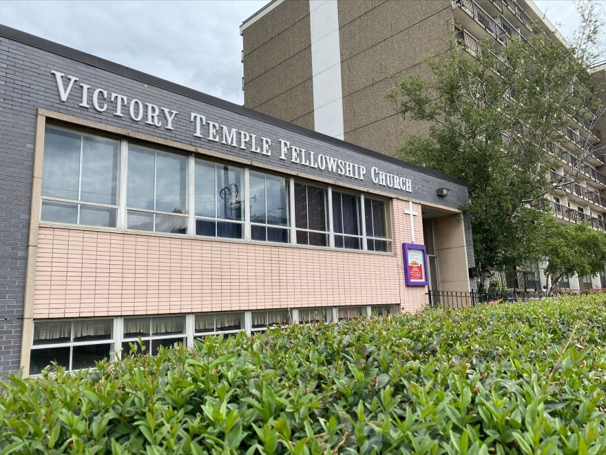 Green shrubbery borders the exterior of Victory Temple Fellowship Church. 