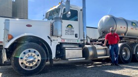 Judd Perry poses next to a large semi truck with the Ottawa Cooperative Association logo plastered on the door to the truck. 