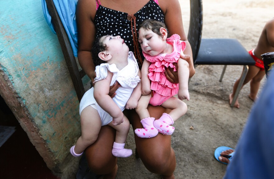 A family member holds twins Eloisa (left) and Eloa, both 8 months old and born with microcephaly, during a Christmas gathering. The mother of the twins, Raquel, who lives in Brazil, said she contracted Zika during her pregnancy.
