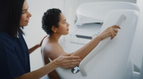 A medical provider guides a patient through the mammogram process.