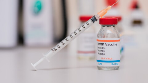 measles mumps and rubella vaccination concept with syringe in vaccine vial and other vials in background